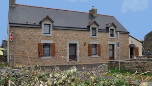 Un bâtiment en pierre avec un toit recouvert de tuiles grises, de nombreuses fenêtres et un panneau de signalisation indiquant un arrêt.
