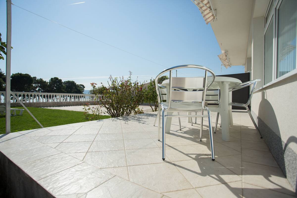 A patio with a white metal chair and a small plant.