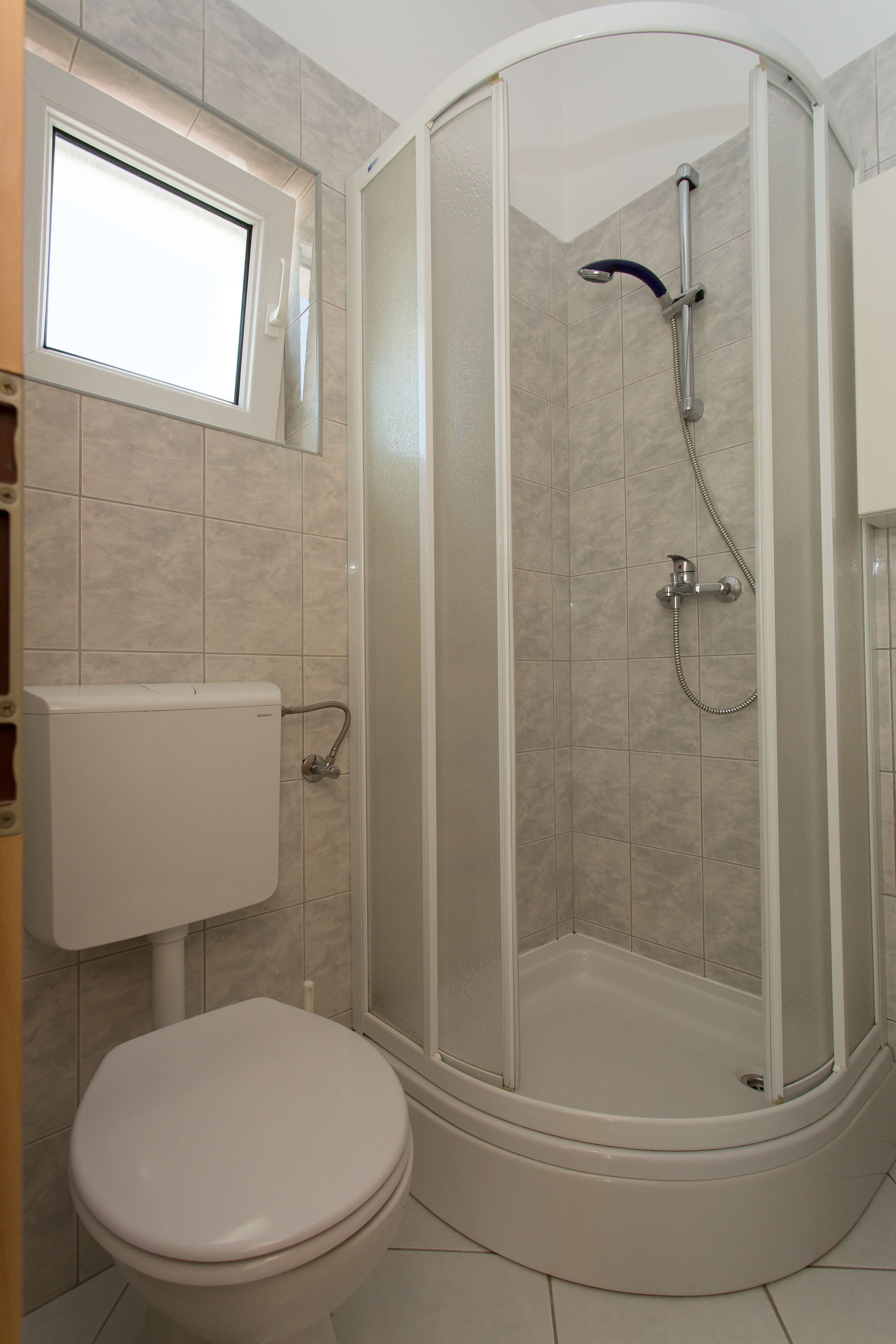 Ein Badezimmer mit Toilette, Duschkabine und Fenster.
