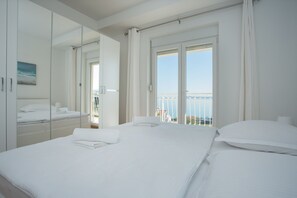 Une chambre d’hôtel avec un grand lit, un miroir et un balcon donnant sur la mer.