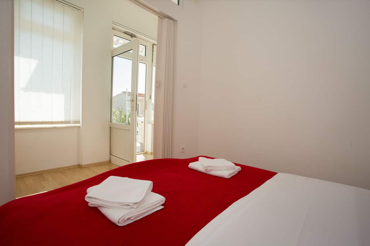 A hotel room with a bed, a red bedspread, and white towels.