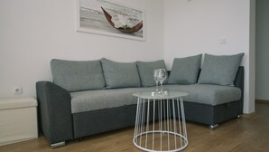 Un canapé gris, une petite table d’appoint blanche et un verre d’eau.