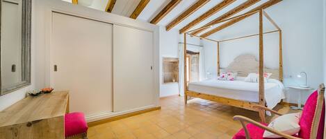 A bedroom with a wooden ceiling, a bed, a chair, and a desk.