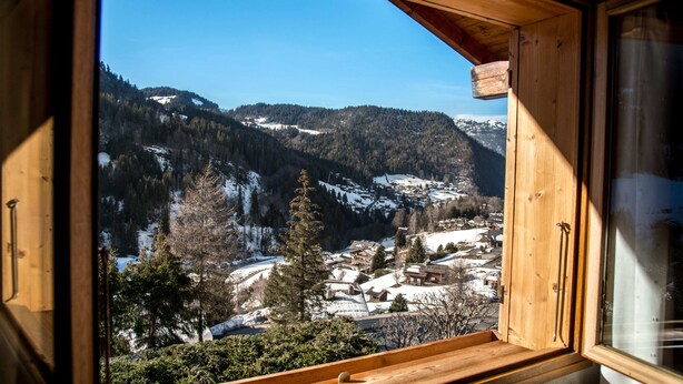 Una cabaña de madera con vistas a un paisaje nevado de montañas.