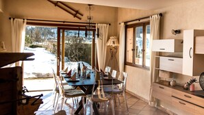 Un comedor con una mesa dispuesta para cuatro personas, un aparador de madera y vistas a un paisaje nevado a través de la ventana.
