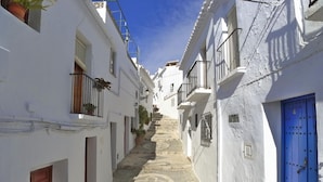 A narrow street with white buildings, blue doors, and a staircase leading to a higher level. - 3 Bedrooms | Aljamar 19A | CG  R1086 (Nerja)
