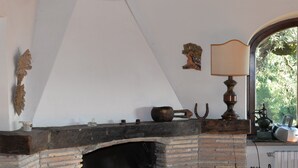 A rustic fireplace with a brick surround, a wooden mantel, and a hanging lamp.