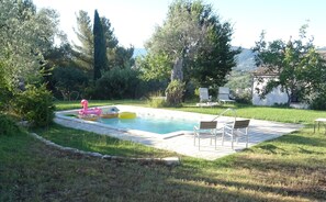 Piscina com espreguiçadeiras e brinquedos infláveis.
