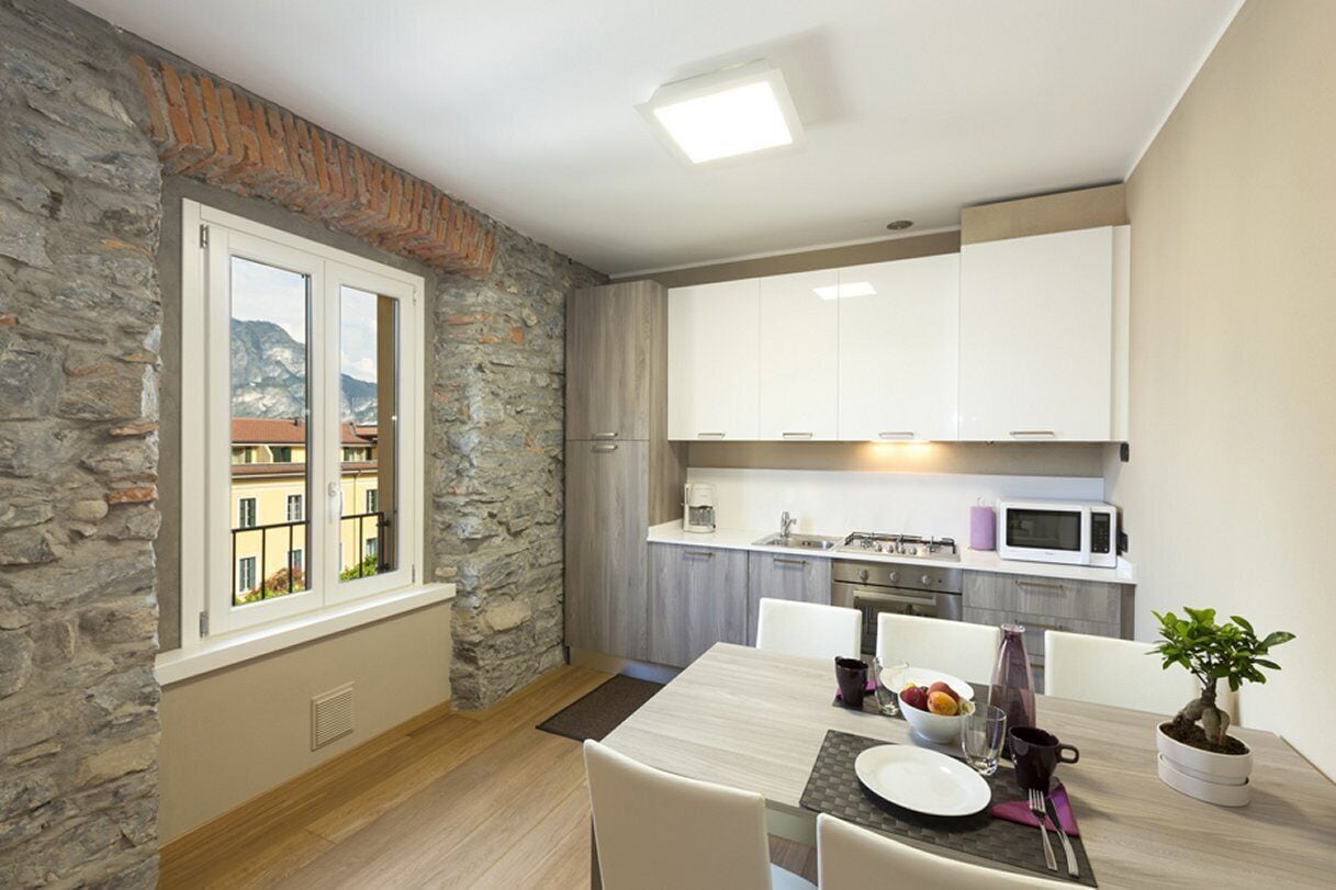 Una cucina moderna con mobili bianchi, un forno a microonde e un'area pranzo con un tavolo apparecchiato per due.
