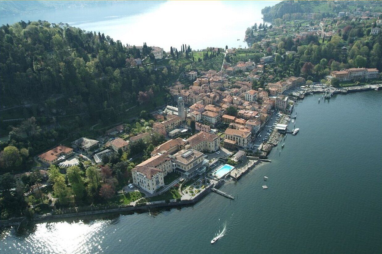 Vista aerea di una cittadina sulle rive di un lago, con edifici, un molo e barche.