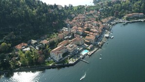 An aerial view of a lakeside town with buildings, a dock, and boats.
