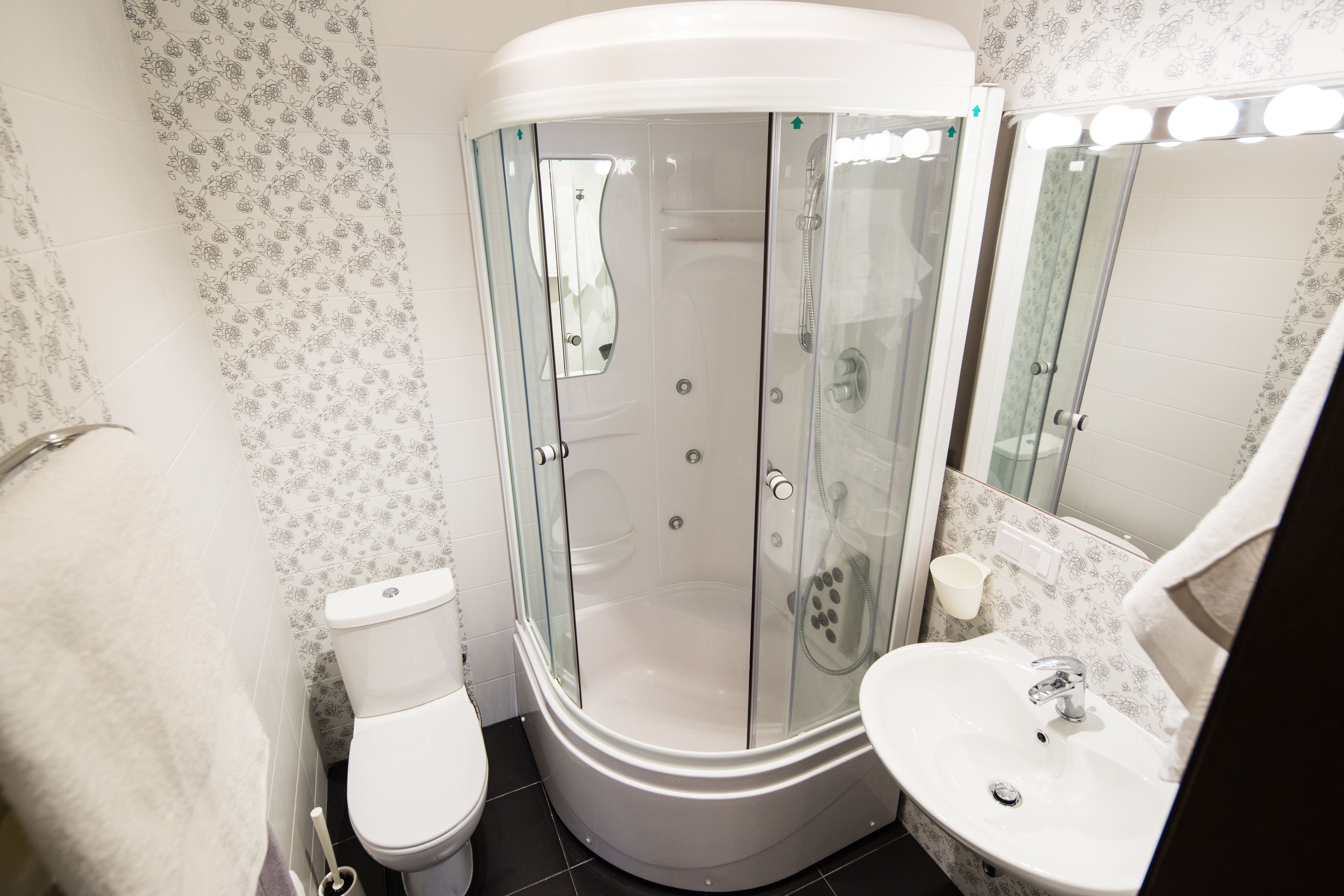 A modern bathroom with a glass-enclosed shower, a white toilet, and a sink with a mirror above it.