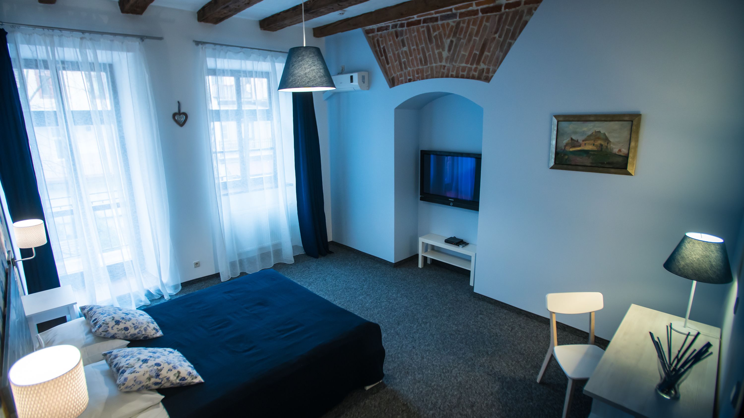 A bedroom with a bed, a TV, a desk, and a chair.