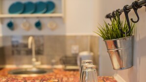 A kitchen counter with a decorative backsplash, a hanging metal bucket with a plant, and a clear glass bottle. - Central Hotel (Lviv)
