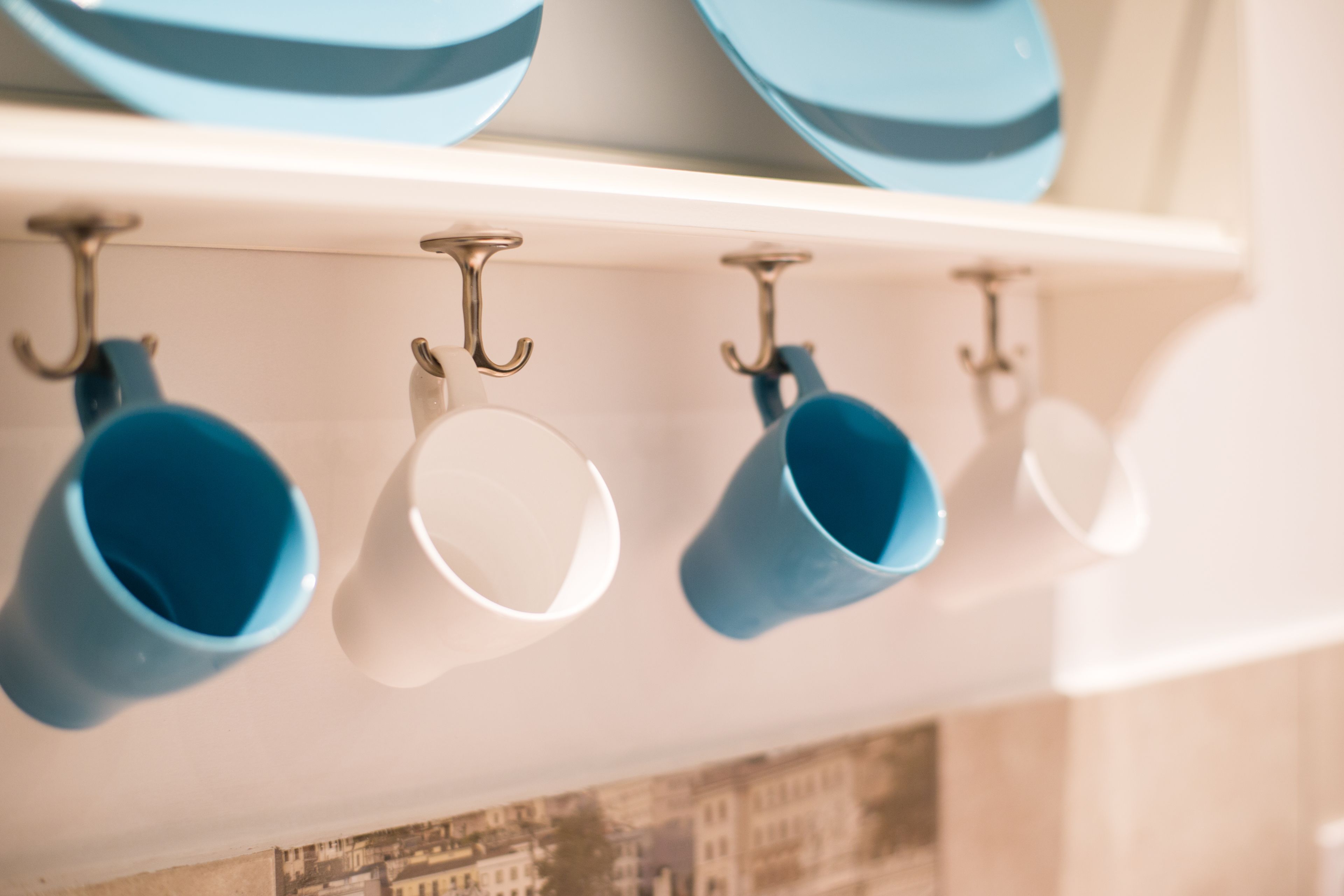 A kitchen with a white shelf holding blue and white mugs and plates.
