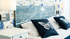 A bedroom with a wooden headboard, two nightstands, a bed with dark blue pillows, and a floral wallpaper. - Central Hotel (Lviv)