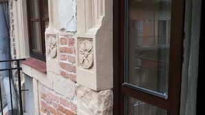 A corner of a building with a stone and brick facade, a window with a glass door, and a tiled floor. - Central Hotel (Lviv)