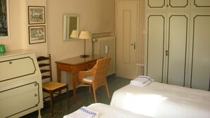 Une chambre d’hôtel comprenant un lit, un bureau, une chaise, une commode, un radiateur et une armoire.