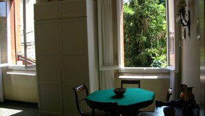 Une pièce comprenant une table à manger, des chaises, une fenêtre donnant sur la forêt et un buffet.