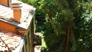 Un bâtiment doté d’un toit en tuiles et d’un jardin verdoyant agrémenté d’arbres et d’arbustes.