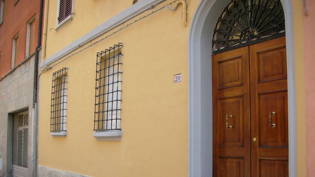 Un bâtiment jaune avec des fenêtres grillagées et une grande porte en bois.
