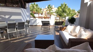 An outdoor patio area with a wicker sofa, a dining table with chairs, and a lounge chair. - Beachfront Newly Renovated Duplex with Sea Views (Marbella)