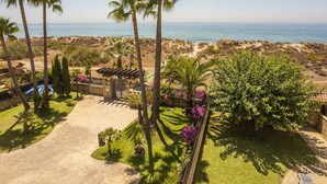 A coastal property with palm trees, a paved patio, and a view of the beach. - Beachfront Newly Renovated Duplex with Sea Views (Marbella)