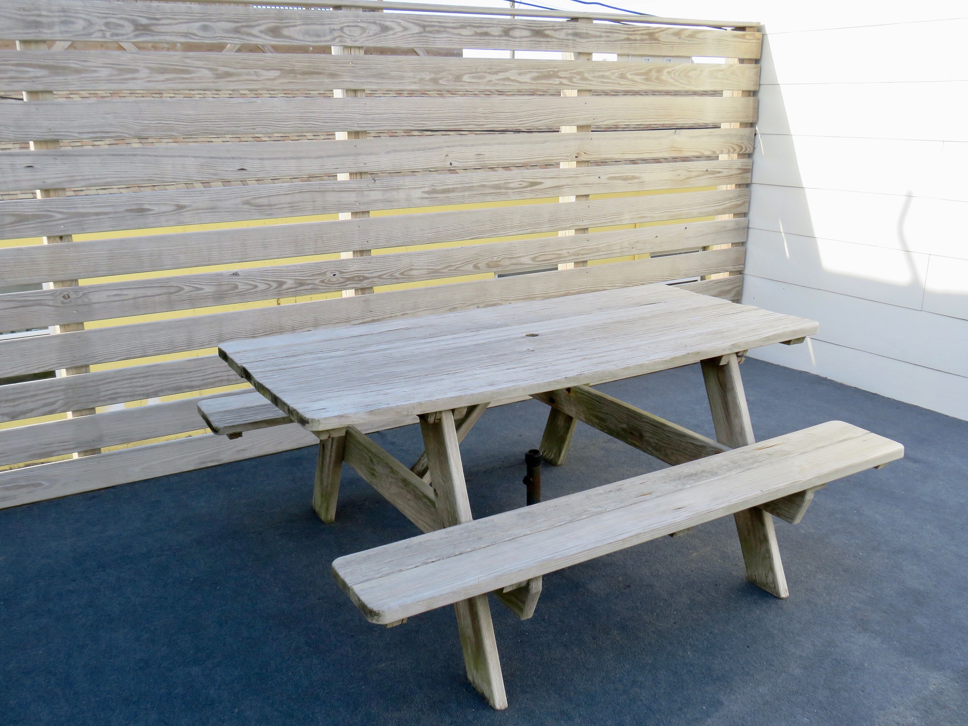 A wooden bench with a backrest and a bench seat, positioned on a concrete floor.