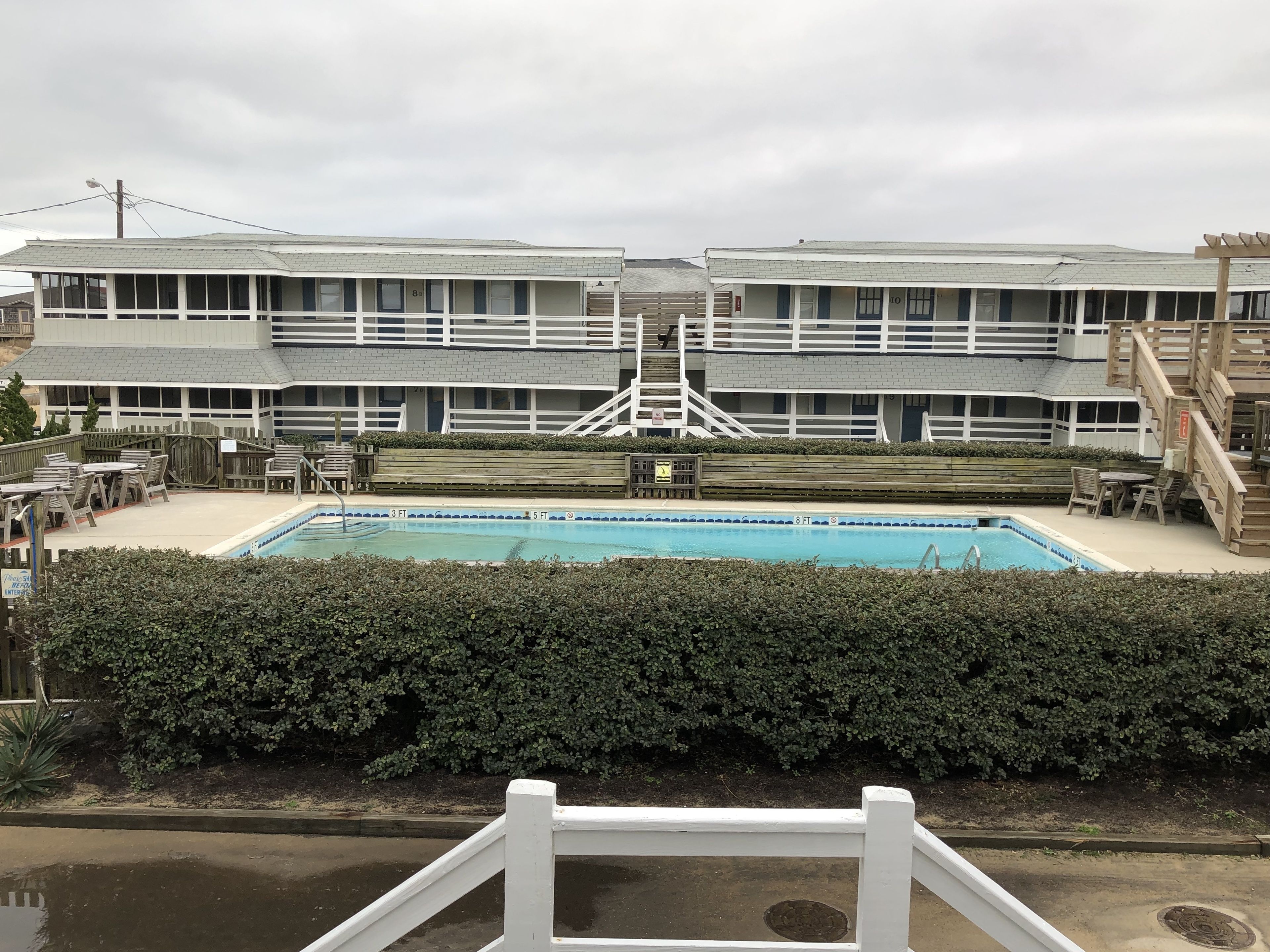 A hotel with a pool, outdoor seating, and a staircase leading to the upper floors.