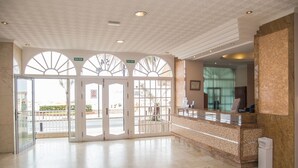 A spacious lobby with a reception desk, a glass door entrance, and a ceiling with a patterned design.