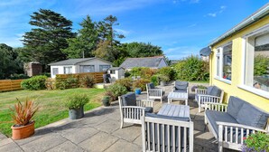 A patio with outdoor furniture, a garden, and a house in the background. - GORGEOUS SPACIOUS  FAMILY HOUSE IN THE CENTRE OF ABERSOCH (Abersoch)