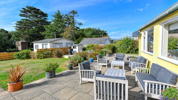 A patio with outdoor furniture, a garden, and a house in the background. - GORGEOUS SPACIOUS  FAMILY HOUSE IN THE CENTRE OF ABERSOCH (Abersoch)