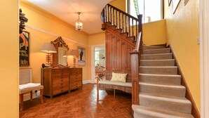 A wooden herringbone floor, a wooden staircase with carpeted steps, a wooden bench with cushions, and a wooden dresser with a lamp. - GORGEOUS SPACIOUS  FAMILY HOUSE IN THE CENTRE OF ABERSOCH (Abersoch)