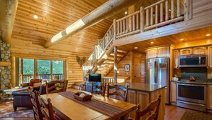 A log cabin interior with a dining area, kitchen, and a staircase leading to an upper level. - Armstrong Luxury Log Vacation  At Windcliff 4 Bedroom Home by RedAwning (Estes Park)