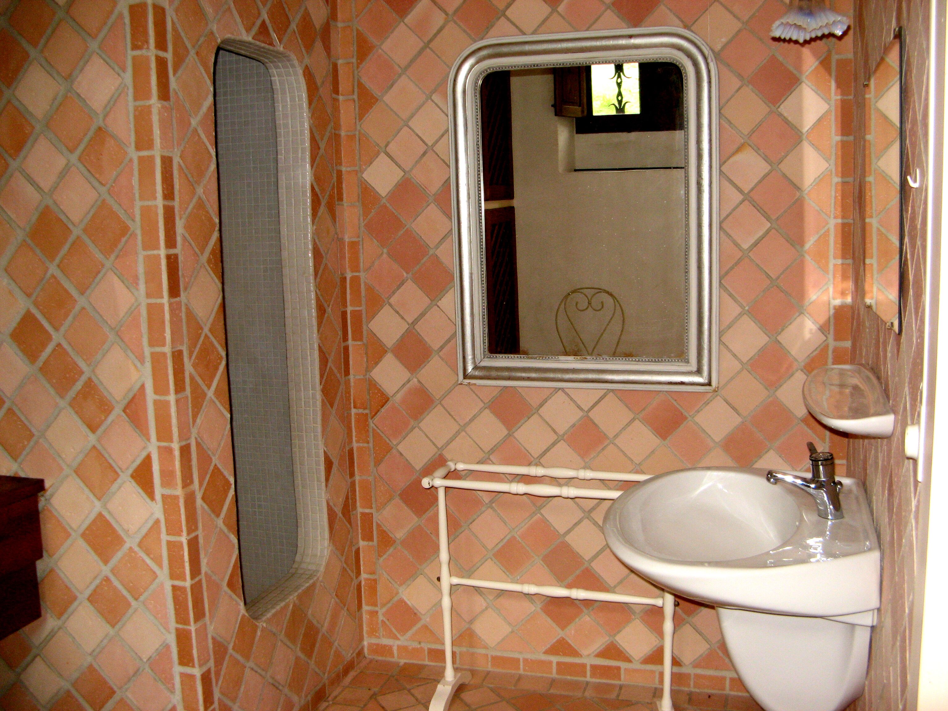 Une salle de bain avec un sol carrelé, un lavabo, un miroir et un porte-serviettes.