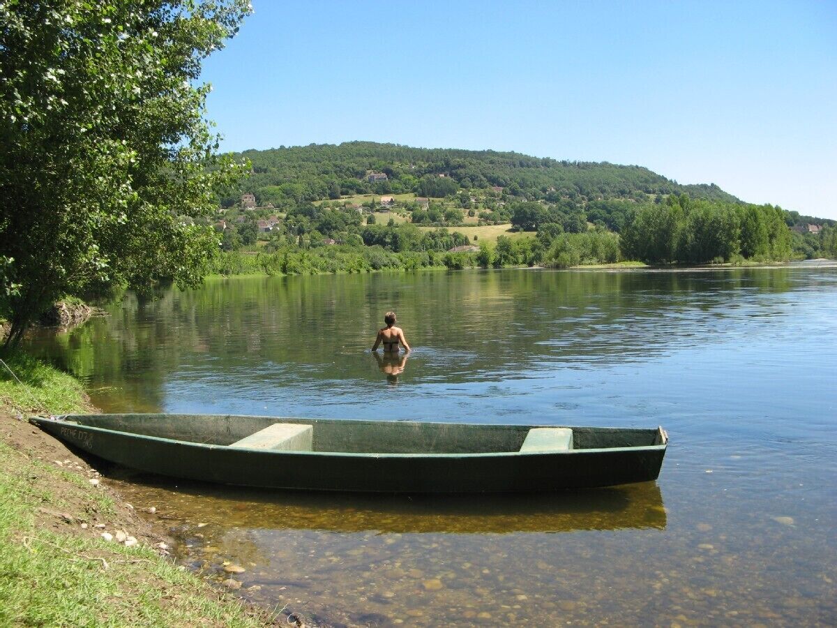 Un río tranquilo con una pequeña embarcación y una persona en el agua.