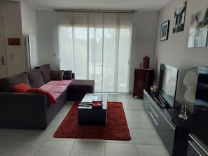A living room with a sectional sofa, a coffee table, a flat-screen TV, and a fireplace.