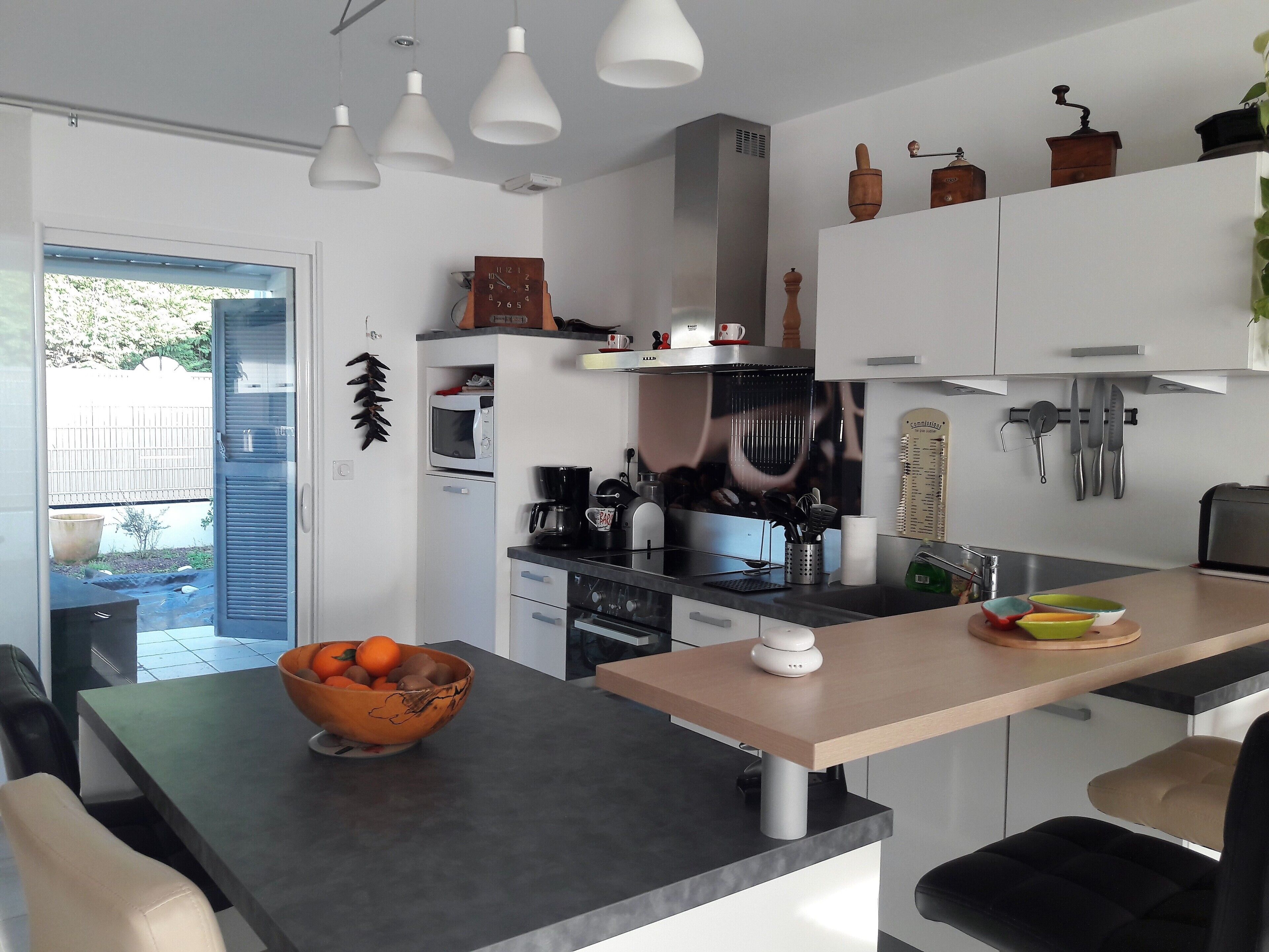 A modern kitchen with a central island, a microwave, a coffee maker, and various utensils.