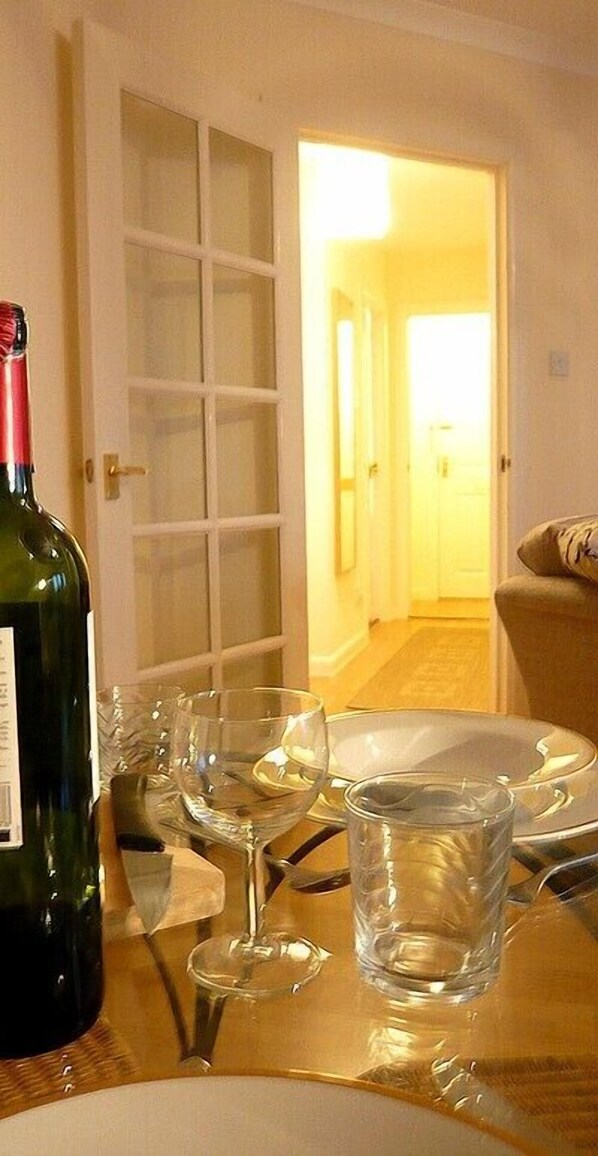 A dining table with a bottle of wine, several glasses, and plates, suggesting a meal setting.