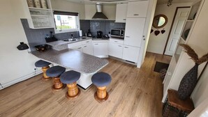 Une cuisine moderne dotée d’un plan de travail en granit, de meubles blancs et d’un îlot central avec des tabourets de bar.