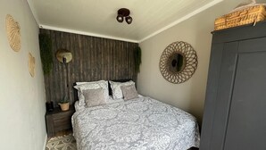 Une chambre à coucher comprenant un lit, une armoire, un luminaire au plafond et un miroir fixé au mur.