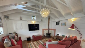 Ein geräumiges Wohnzimmer mit einem großen roten Sofa, einem an der Wand montierten Fernseher, einem Kamin und einer Kristallleuchter.