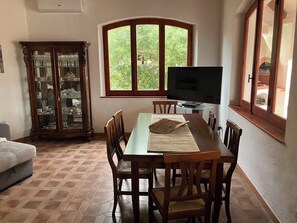 A dining area with a table, chairs, a television, and a cabinet with glass doors. - beautiful typical Sardinian villa 300 meters from the sea, 2 bedrooms, 2 bathro (La Ciaccia (Valledoria))