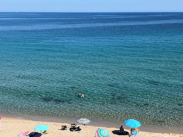 A beach with clear water, a few people swimming, and several beach umbrellas. - beautiful typical Sardinian villa 300 meters from the sea, 2 bedrooms, 2 bathro (La Ciaccia (Valledoria))