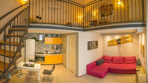 Un apartamento moderno con cocina, comedor y un sofá rojo.