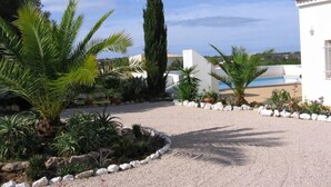 A courtyard with a pool, palm trees, and a white building with a clock tower. - Holiday apartment ideal for a couple with private Swimming pool (Carvoeiro)