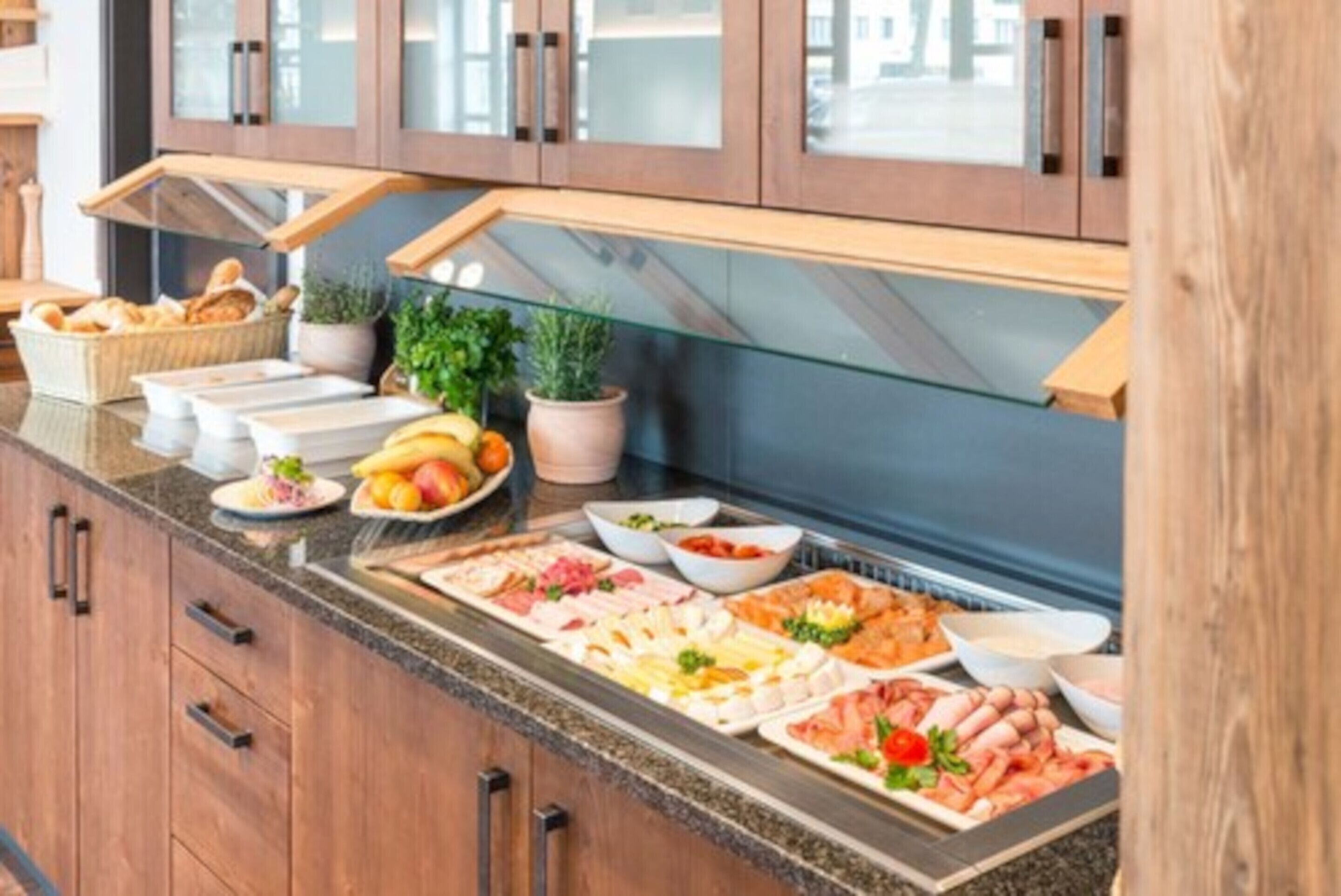 A buffet with various food items and a wooden cabinet in the background.