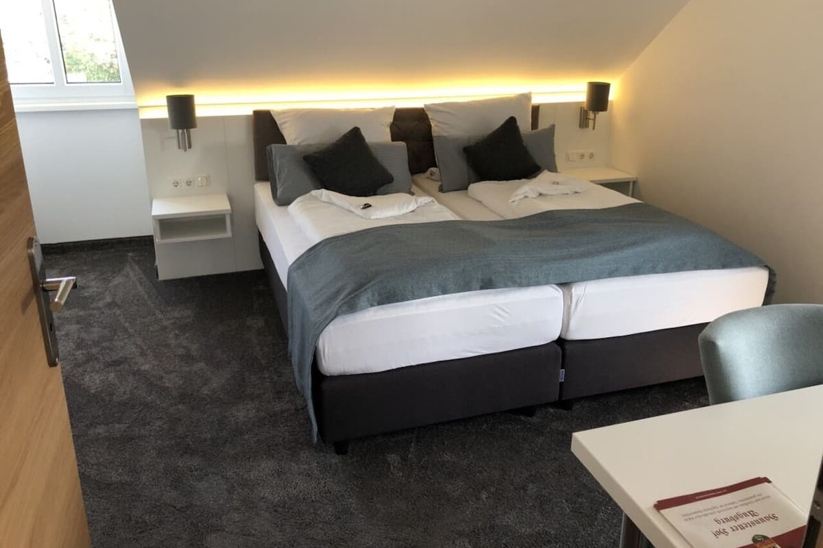Een moderne hotelkamer met een groot bed, nachtkastjes en een klein bureau.
