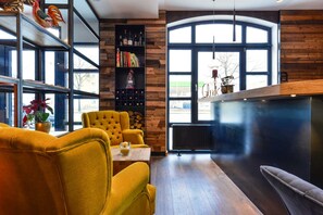 Un intérieur moderne avec un fauteuil jaune, une bibliothèque en bois et une grande fenêtre donnant sur un beau paysage.