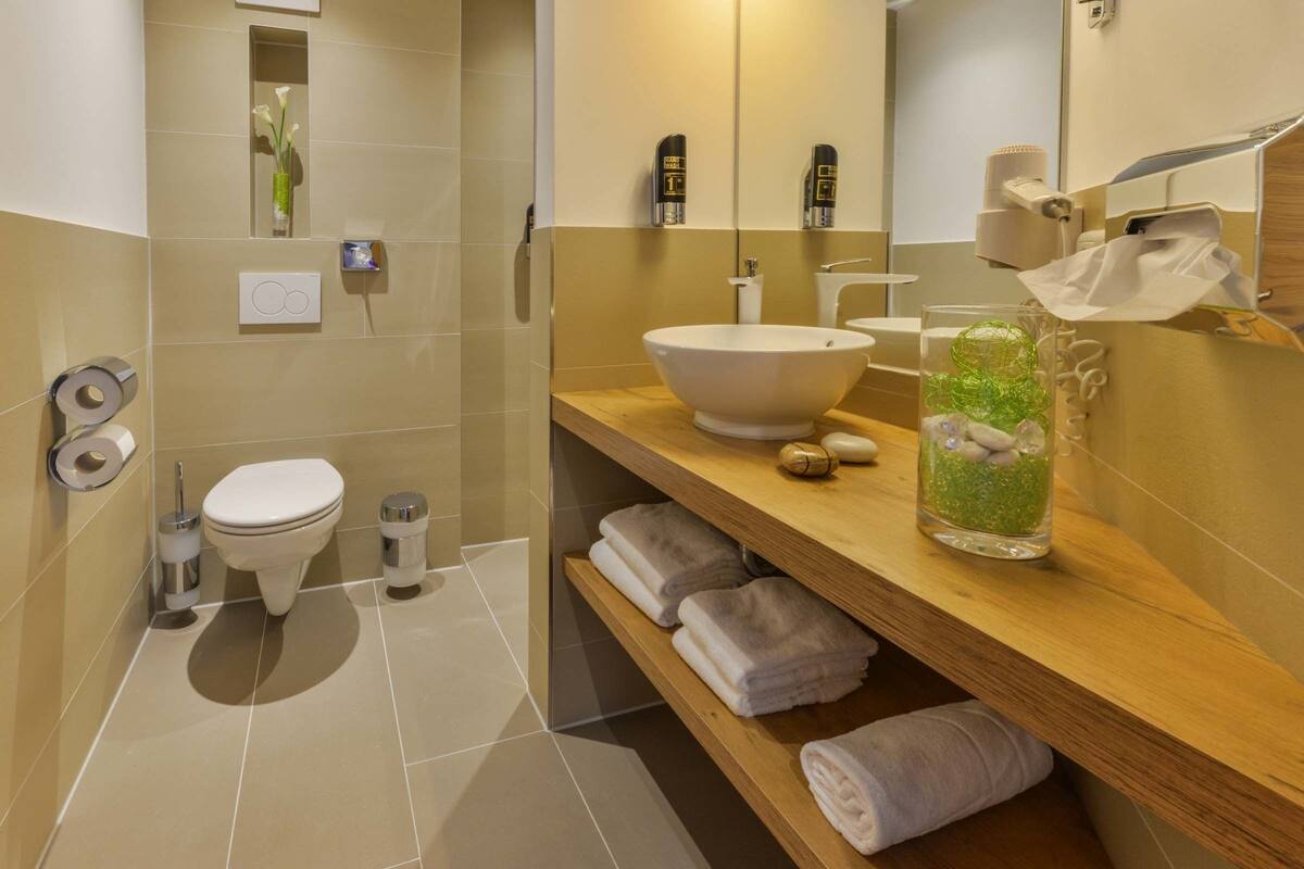 Een moderne badkamer met toilet, wastafel en planken met handdoeken.